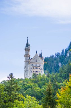 Neuschwanstein, ünlü masal kalesi, prensesler ve sevgililer, mavi gökyüzüne ve ormanlara karşı durur göllerin arka planına karşı