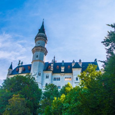 Neuschwanstein, ünlü masal kalesi, prensesler ve sevgililer, mavi gökyüzüne ve ormanlara karşı durur göllerin arka planına karşı