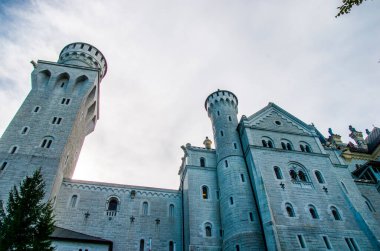 Neuschwanstein, ünlü masal kalesi, prensesler ve sevgililer, mavi gökyüzüne ve ormanlara karşı durur göllerin arka planına karşı