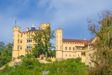 Hohenschwangau, ünlü ortaçağ şatosu, ejderhalarla, şövalyelerle ve prenseslerle, mavi göllerin karanlık ormanlarının arka planına karşı.
