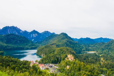 Hohenschwangau, ünlü ortaçağ şatosu, ejderhalarla, şövalyelerle ve prenseslerle, mavi göllerin karanlık ormanlarının arka planına karşı.