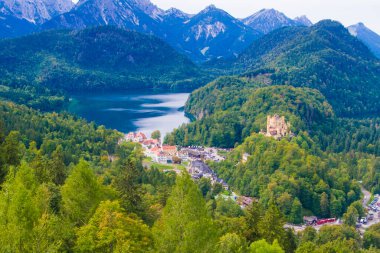 Hohenschwangau, ünlü ortaçağ şatosu, ejderhalarla, şövalyelerle ve prenseslerle, mavi göllerin karanlık ormanlarının arka planına karşı.