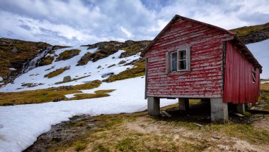 Karlı bir tarlanın ortasında kırmızı bir kulübe