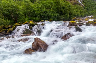 Önünde şelale ve kayalar olan bir nehir.