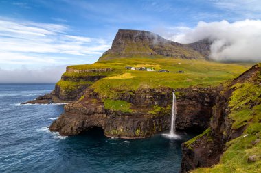 Yeşil bir dağın ortasında bir şelale.