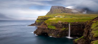 Yeşil bir dağın ortasında bir şelale.