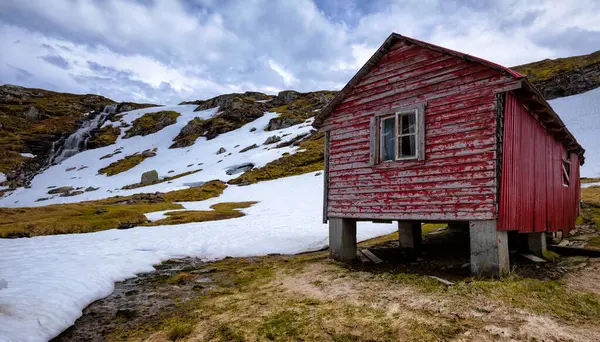 Karlı bir tarlanın ortasında kırmızı bir kulübe