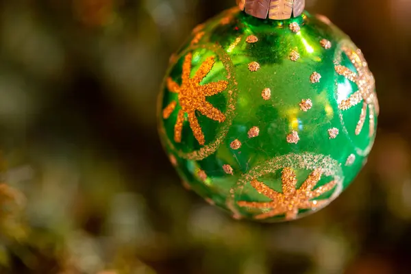 Ağaçtan sarkan yeşil bir Noel süsü.