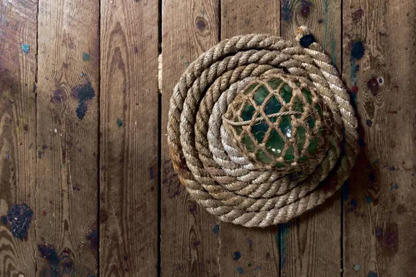 Bir ip ve ahşap zeminde yeşil bir top.