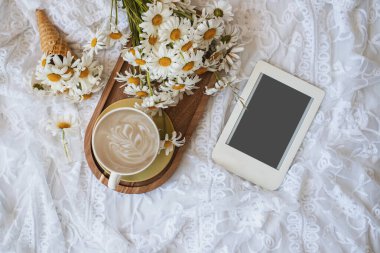 Yaz ya da bahar evi kompozisyonu, bir buket papatya, bir fincan sabah kahvesi ve e-kitap. Kadınsı blog sosyal medya şablonu.