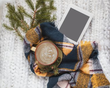 Kış kompozisyonu, bir fincan kahve, sıcak ekose eşarp, fotokopi alanı ve ladin dallı e-kitap. Noel sabahı. Hygge ev içi..