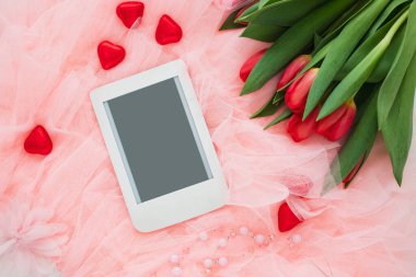 E-kitap okuyucusuyla romantik kompozisyon, bahar laleleri ve pembe arka planda bir fincan kahve. Kadınsı blog sosyal medya şablonu. Anneler günün kutlu olsun.. 