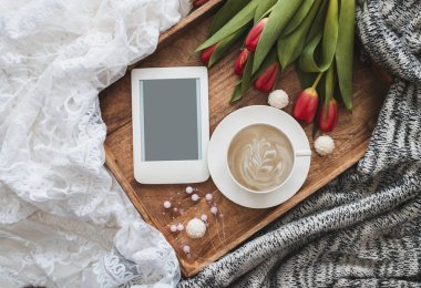 Romantik kompozisyon, bir fincan kahve, kırmızı laleler ve ahşap tepside fotokopi alanı olan e-okuyucu. Kadınsı blog sosyal medya şablonu.