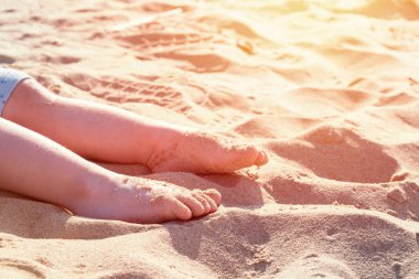 Güneşin altında, denizin kenarında, kumların üzerinde çocuk ayakları. Yaz tatili.