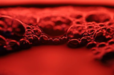 Kabarcıklı kırmızı sıvı, kremsi sıvı, makroda kozmetik, beyaz fotokopi alanı, gökkuşağı yansımaları, temiz arkaplan, soyut