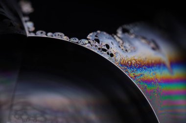 Sıvının makrodaki parlak gökkuşağı yansıması, gümüş renkleri, sürrealist arka plan, fantastik düz hareket, karanlık desen 