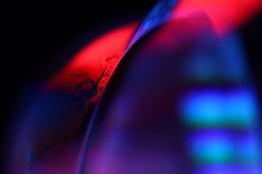 Siyah zemin üzerinde kırmızı ve mor sıvı yansımaları, sıvı yüzey soyutlaması, renk kenarı, derin koyu arkaplan, geometrik su şekilleri, sıvı hareketleri, olağanüstü fiziksel özellikler