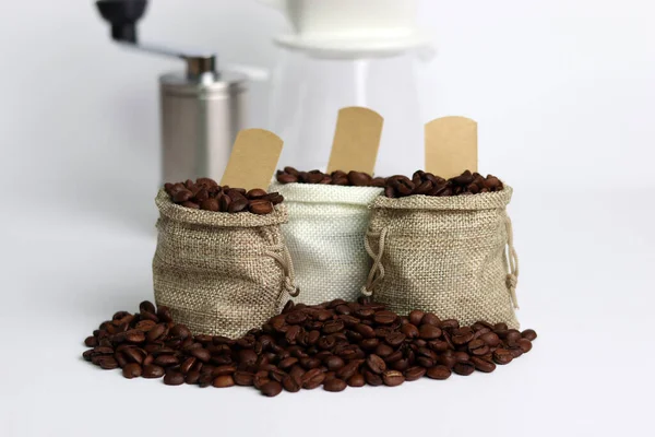 Coffee beans in burlap bags and coffee grinder on white background. Close-up image with coffee beans.