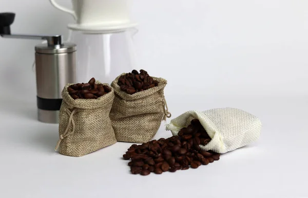 Coffee beans in burlap bags and coffee grinder on white background. Close-up image with coffee beans.