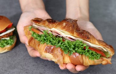 Sandviç tutan bir elin görüntüsünü kapat. Sebzeli ekmek ve jambon..