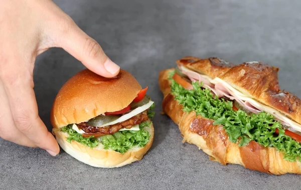 靠近一个手持汉堡包的手的图像 面包加蔬菜和肉饼 — 图库照片