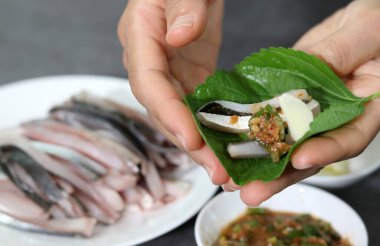 Susam yaprağına sarılmış taze taşlık saşimi görüntüsü. Beyaz tabakta taze sashimi..