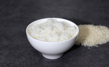 Çiğ pirinç ve pilav. Siyah arka planda beyaz pirinç kasesi..