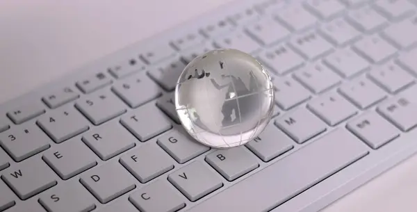 A transparent glass globe on the keyboard. Things and Business Concepts.