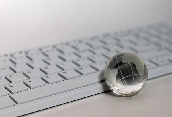 A transparent glass globe in front of the keyboard. Things and Business Concepts.