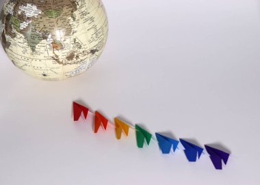 Beyaz bir arka planda küre ve gökkuşağı renkli kağıt uçak. Sosyal çeşitlilik kavramı.