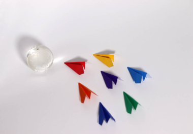 Beyaz bir arka planda küre ve gökkuşağı renkli kağıt uçak. Sosyal çeşitlilik kavramı.