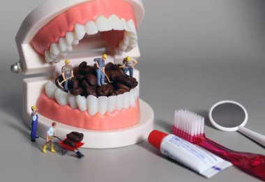 Minyatür insanlar kahve çekirdeklerini ağızlarıyla temizliyorlar. Diş sağlığı bozuk içecek konsepti.