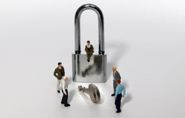 Güvenlik anahtarı ve beyaz arka plana karşı minyatür girişimci. Kilitleme Sorun Çözme Toplantısı.