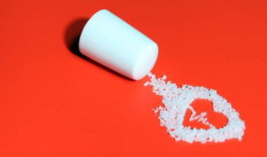 ECG-shaped salt on a red background. Eating salt can increase high blood pressure and heart disease. clipart