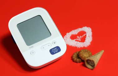 Digital blood pressure monitors and unhealthy food, confectionery, high sugar. Sweet snacks can increase high blood pressure and heart disease. clipart