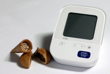 Digital blood pressure monitors and unhealthy food, snacks, high sugar. Obesity can increase high blood pressure and heart disease. clipart
