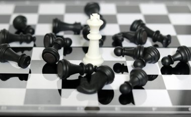 Satranç tahtasının ortasında beyaz bir kral nesnesi. Liderlik ve başarı kavramı. Beyaz Satranç Kralı Siyah Piyonlara Karşı Kazandı. 