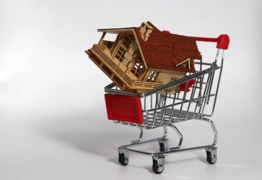 Süpermarket arabasında ahşap bir ev. Ev ya da daire alma fikri. Gayrimenkul yatırımı kavramı.