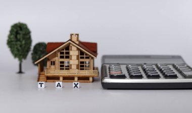 Ahşap evler, ağaçlar, vergi kelimeleri, beyaz arka planda hesap makineleri. İş yatırımı ve emlak vergisi kavramı.