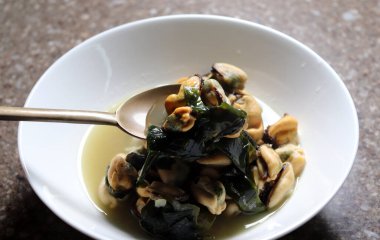 Midye çorbasını beyaz bir kâsede kaşıkla döv. Kore yosunuyla kaynatılmış midye çorbası..