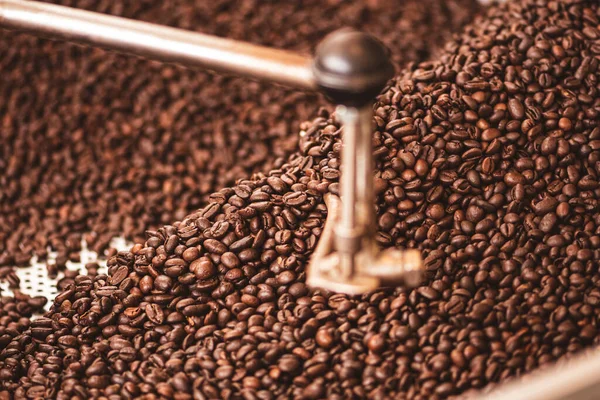Roasting coffee beans in a professional old coffee roasting machine or roaster, close up