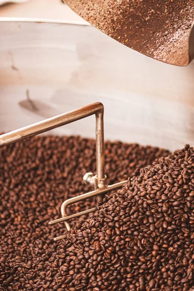 Roasting coffee beans in a professional old coffee roasting machine or roaster, close up, vertical