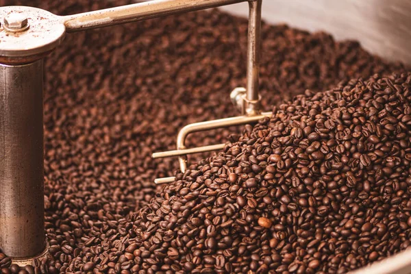 Roasting coffee beans in a professional old coffee roasting machine or roaster, close up