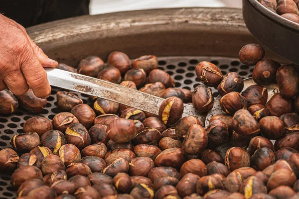 stock image Roasting chestnuts in a bowl or grill on an open fire in a street food market, close up