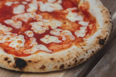 Sıcak pizza Margherita, domates sosu ve ahşap bir tahtanın üzerinde mozzarella ile yemeye hazır, dumanlı, yakın.