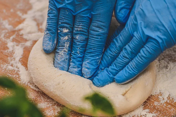 Руки Пластиковых Перчатках Готовят Тесто Пиццы Деревянной Доске Белой Мукой — стоковое фото