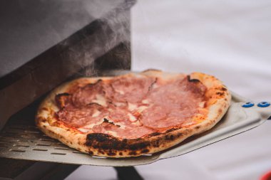 Domates soslu sıcak pizza pişirmek ya da pişirmek, mozzarella ve elektrikli ya da gaz fırınında kürekle salam yemek, dumanla kaplamak.