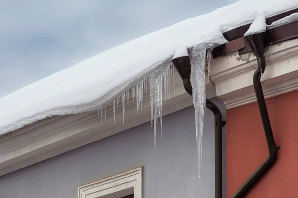 Icicles hanging from a roof of a building in the city in a cold day of winter or spring