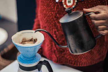Black skin girl preparing or brewing black coffee with a teapot and cloth or paper filter