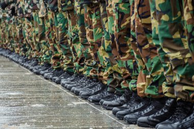 Military boots and camouflage trousers of many soldiers in uniform in a row during a training clipart